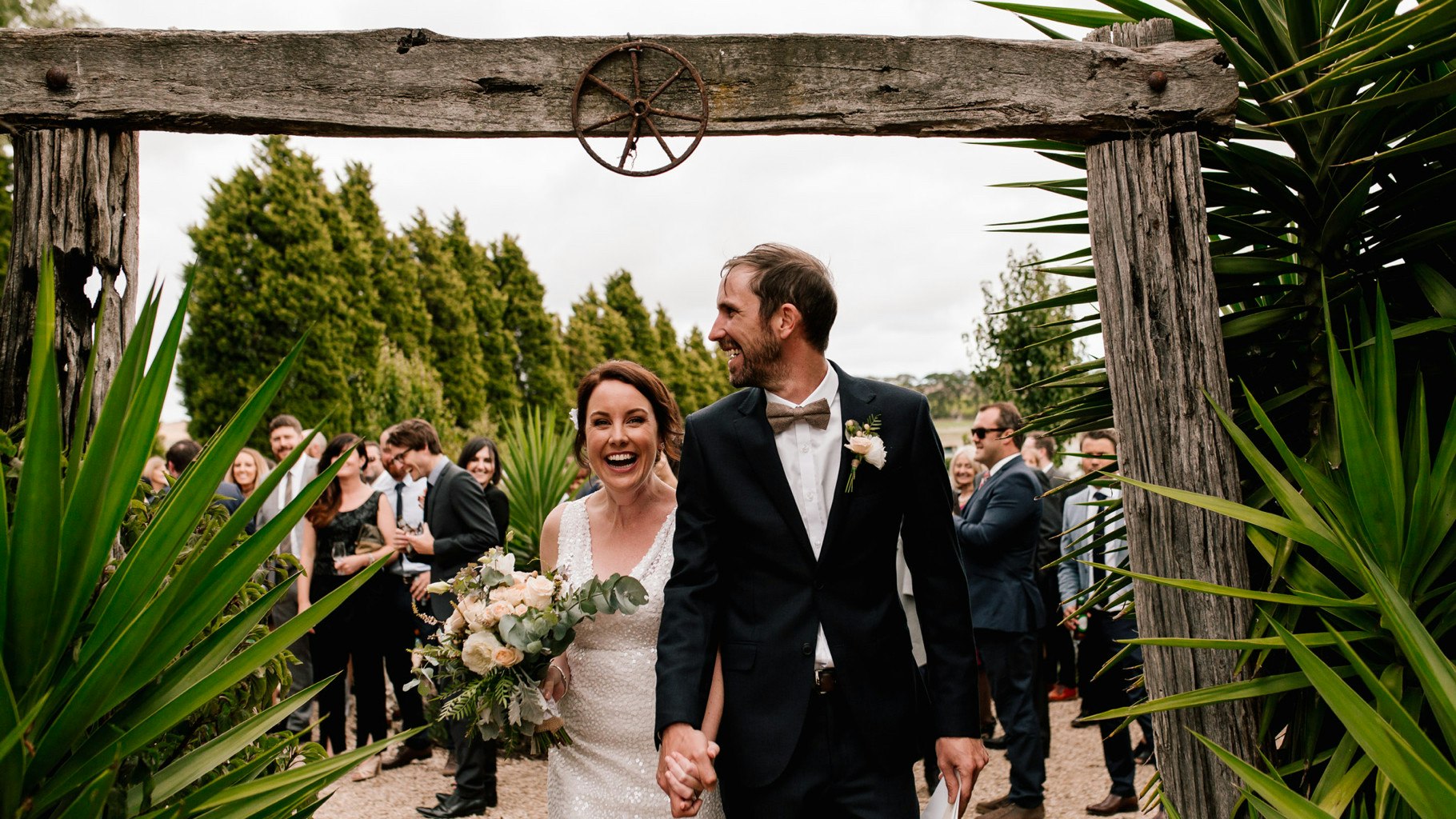 Wedding couple celebrating underneath an archway.